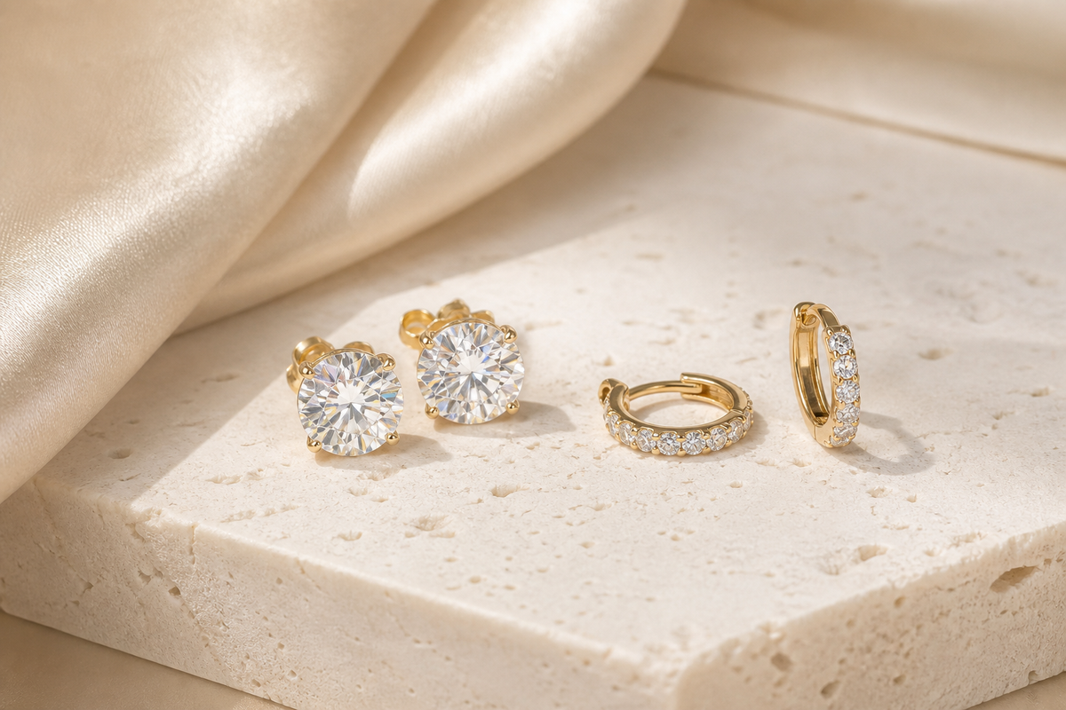 Moissanite stud and hoop earrings styled on warm ivory stone
