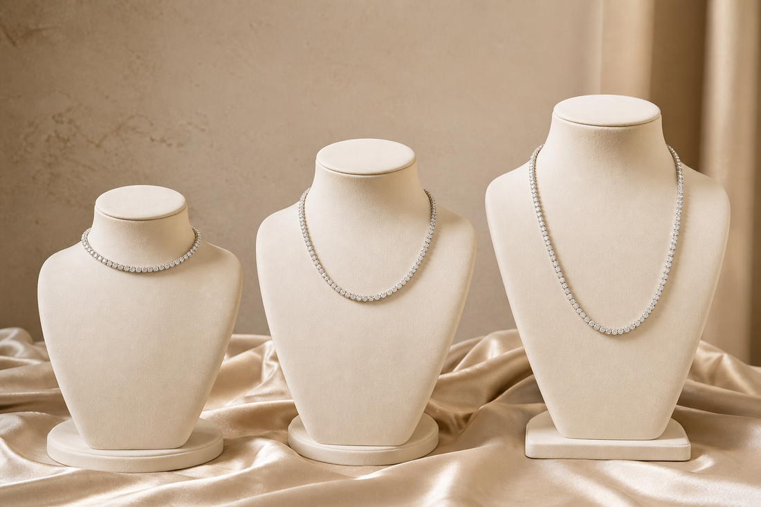 Three tennis necklaces displayed at short, medium and long lengths on ivory stands