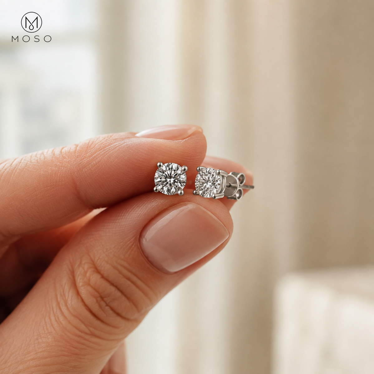 Amelia round moissanite stud earring pair held for scale