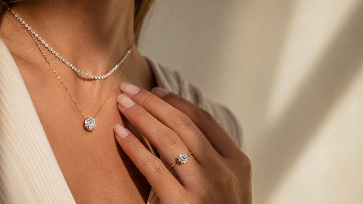 Layered necklaces and a round-stone ring worn with an ivory blouse