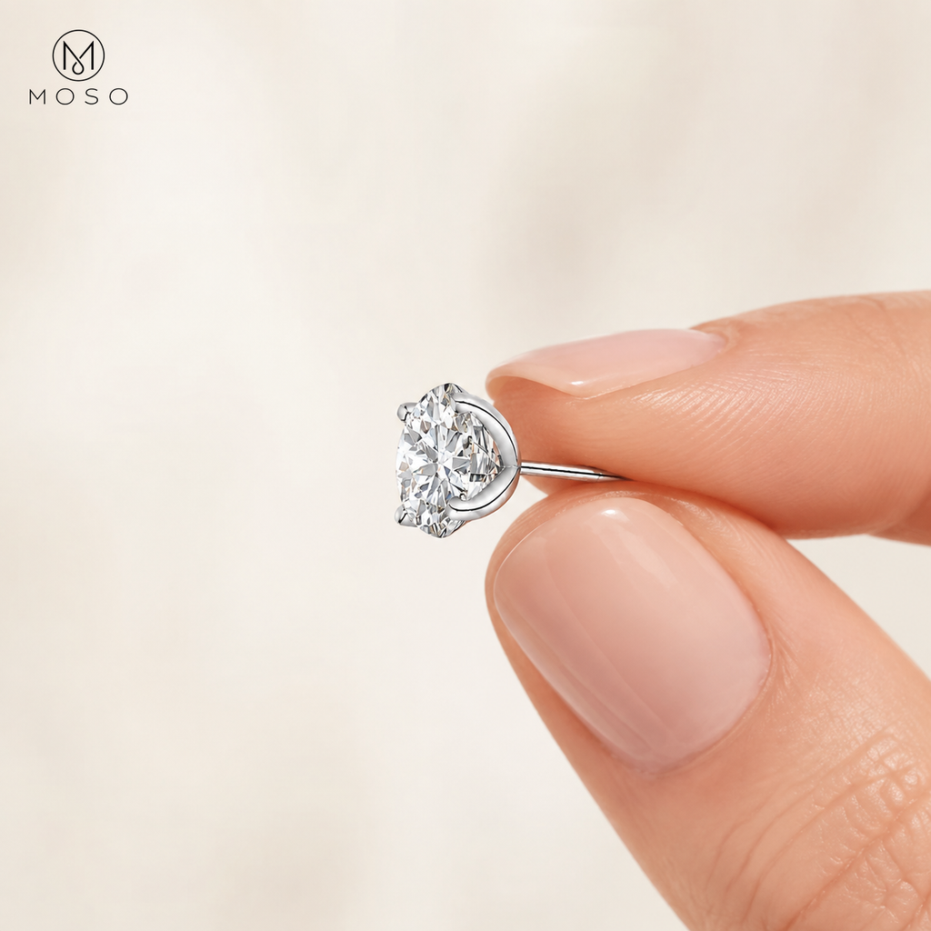 Mia round moissanite stud earring held between fingertips to show scale