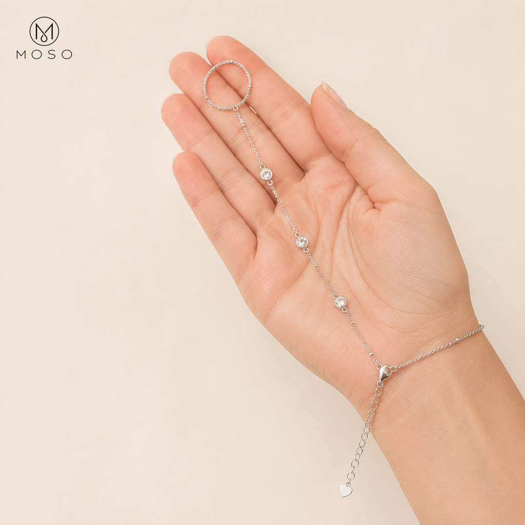Savannah silver tone hand chain bracelet held in an adult hand showing three moissanite stones