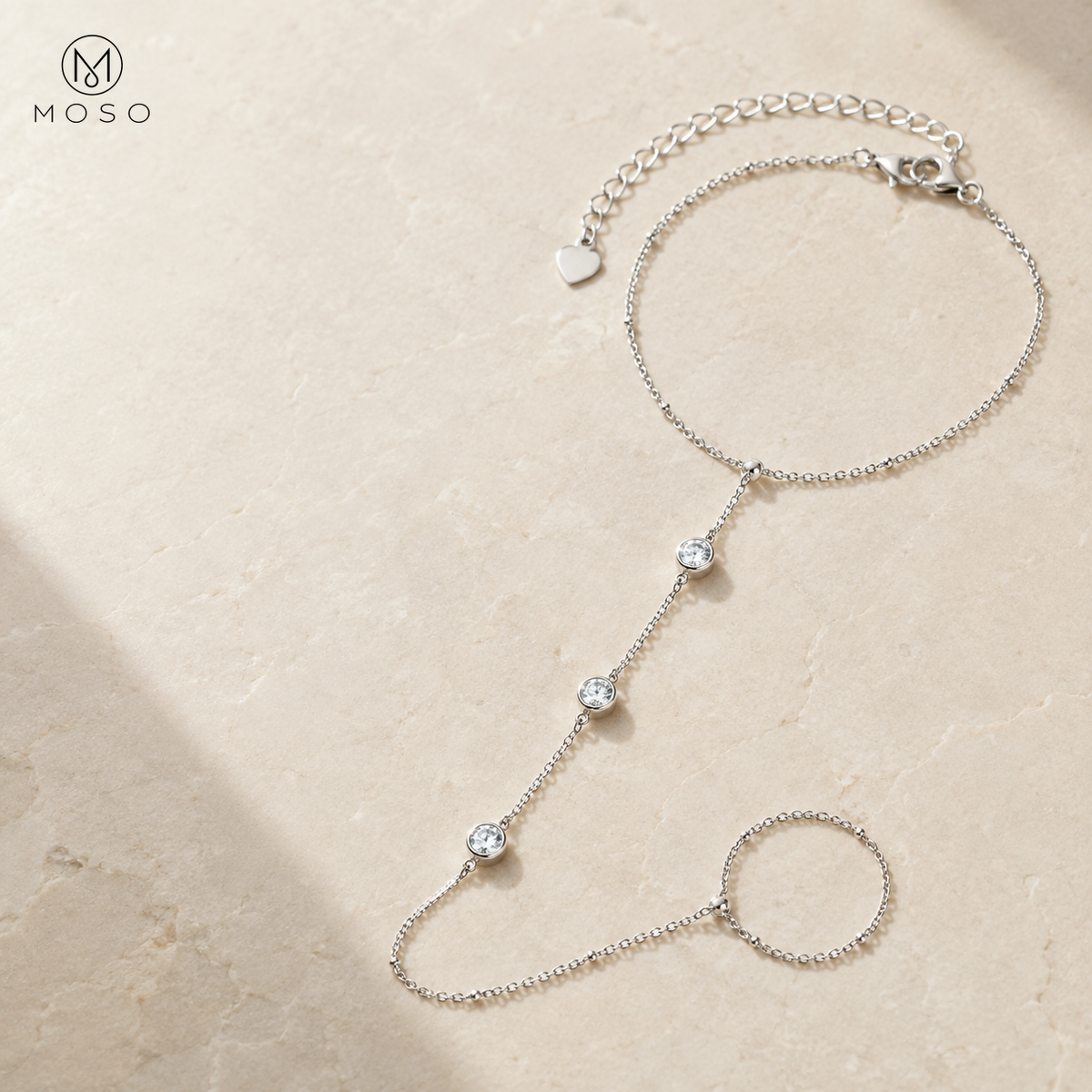 Savannah silver tone hand chain bracelet with three bezel set moissanite stones on pale stone