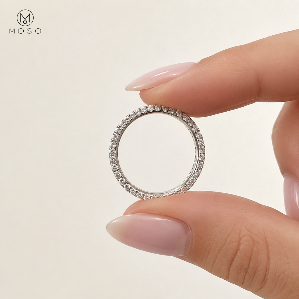 Taylor slim moissanite eternity ring held between fingers